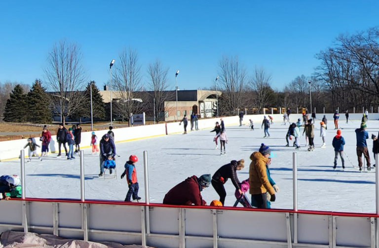 Dozens of skaters of all ages on the open-air rink at Gull Crest on a clear winter day.